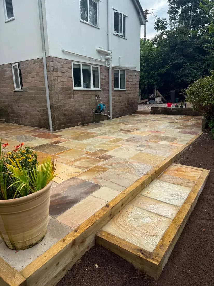Indian sandstone patio with timber sleeper steps down to the garden
